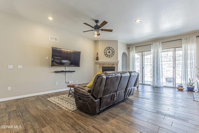 living room with a tiled fireplace, hardwood / wood-style flooring, and ceiling fan