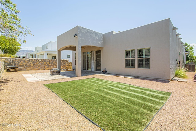 rear view of property featuring a patio area, central AC, a lawn, and an outdoor fire pit