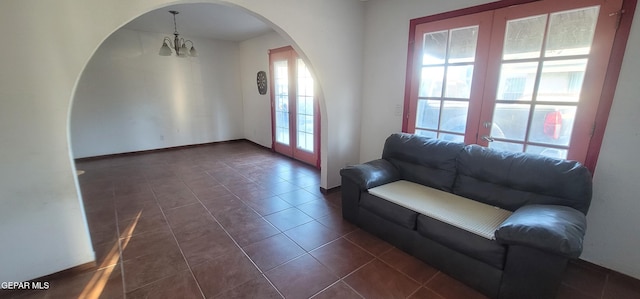 unfurnished living room featuring dark tile patterned floors and an inviting chandelier