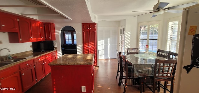 kitchen featuring sink, tile patterned floors, ceiling fan, and a kitchen island