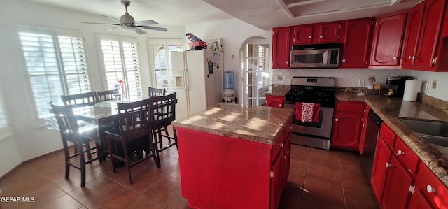 kitchen with a kitchen island, appliances with stainless steel finishes, dark tile patterned floors, and backsplash