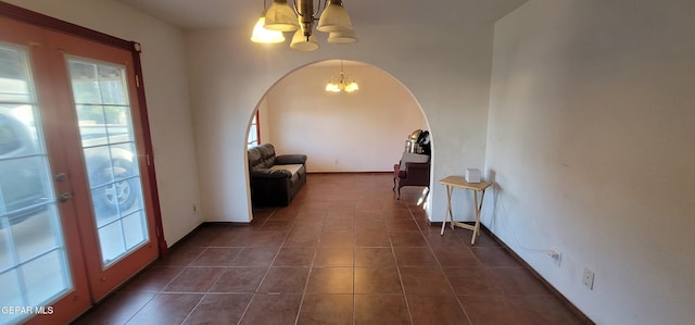 corridor featuring a notable chandelier and dark tile patterned flooring