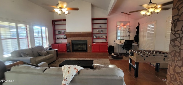 living room featuring ceiling fan, lofted ceiling, a tiled fireplace, and tile patterned flooring