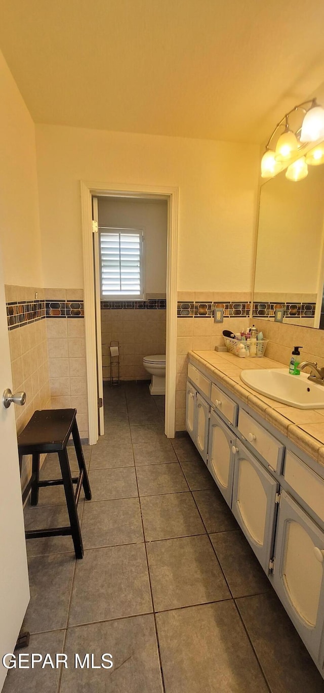 bathroom featuring tile patterned flooring, vanity, tile walls, and toilet