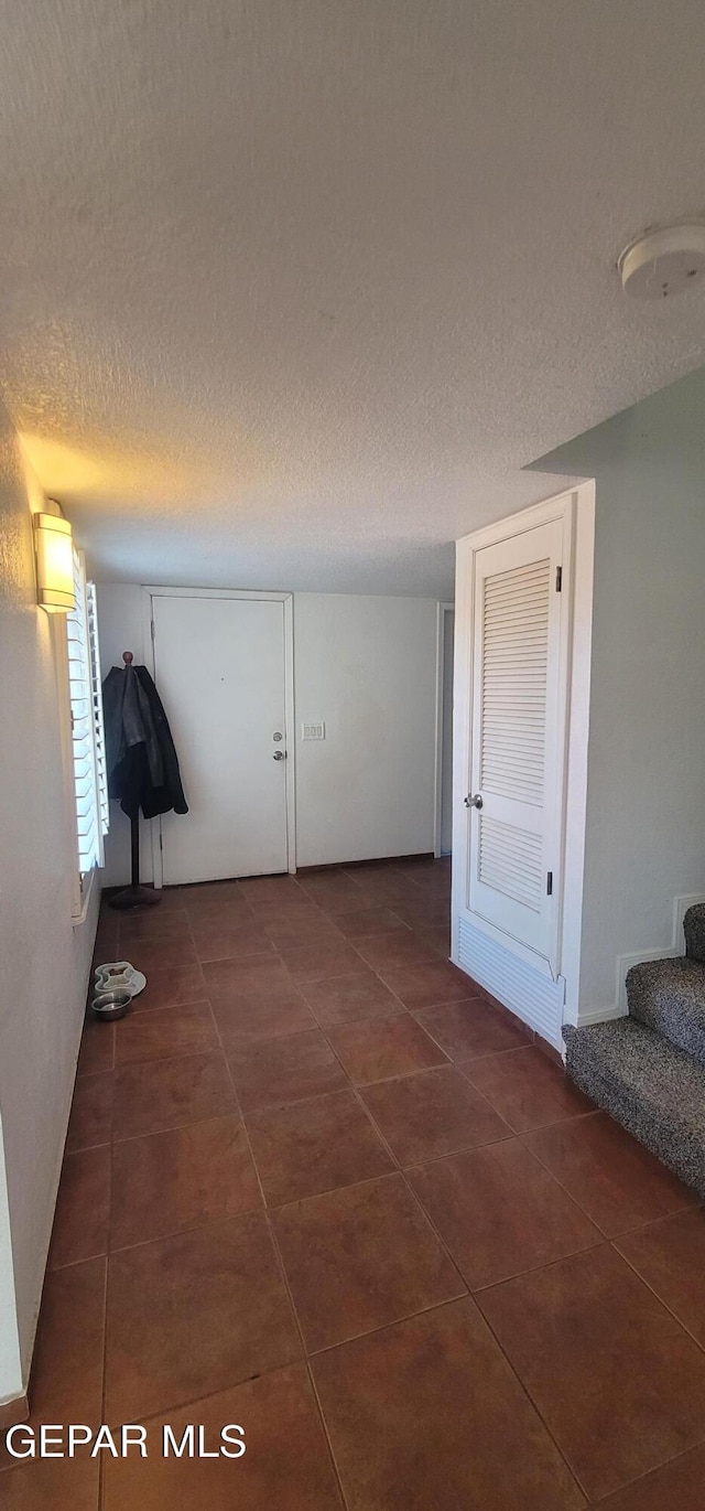 corridor with dark tile patterned flooring and a textured ceiling