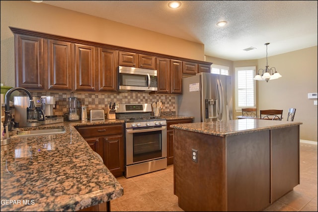 kitchen featuring a kitchen island, appliances with stainless steel finishes, sink, dark stone countertops, and decorative backsplash