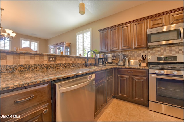 kitchen with pendant lighting, sink, plenty of natural light, stainless steel appliances, and tasteful backsplash