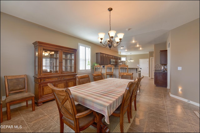 dining area with a chandelier and dark tile patterned flooring