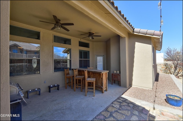 view of patio with exterior bar and ceiling fan