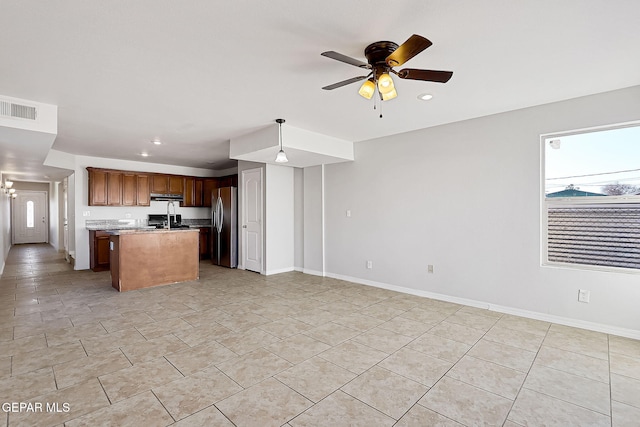 kitchen featuring stainless steel refrigerator with ice dispenser, range, light tile patterned floors, a kitchen island, and ceiling fan with notable chandelier