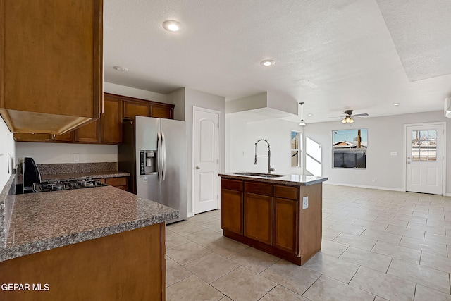 kitchen featuring sink, light tile patterned floors, stainless steel fridge, ceiling fan, and a kitchen island with sink