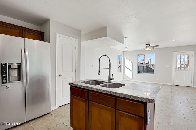 kitchen with sink, a center island with sink, light tile patterned floors, stainless steel fridge, and ceiling fan