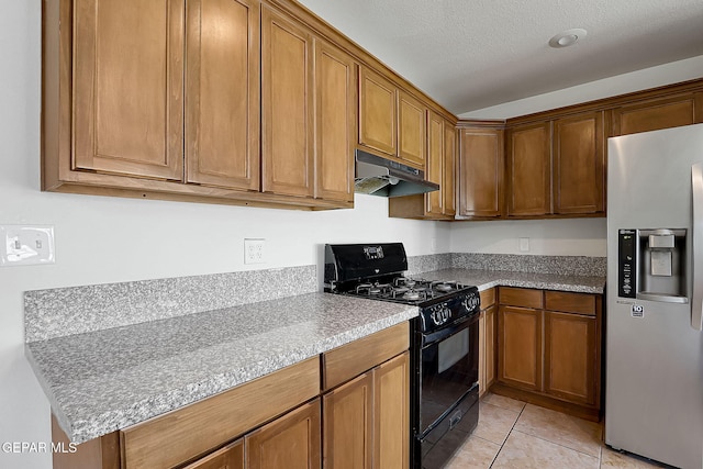 kitchen featuring light tile patterned flooring, black gas range oven, stainless steel fridge, and a textured ceiling