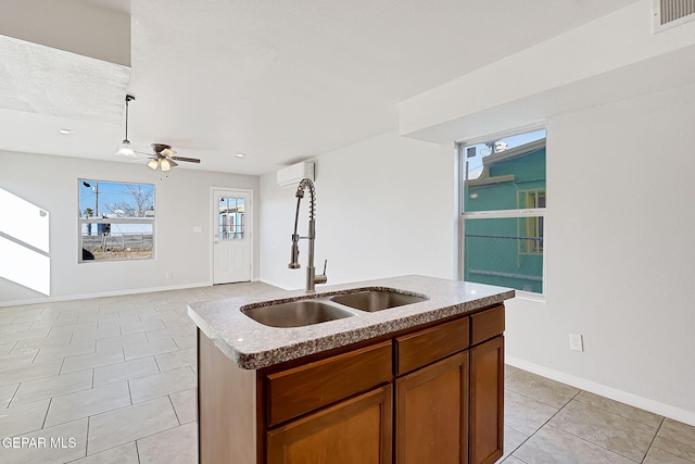 kitchen with light tile patterned flooring, sink, a kitchen island with sink, ceiling fan, and a wall unit AC