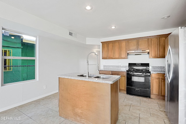 kitchen with light tile patterned flooring, sink, stainless steel refrigerator, black gas stove, and a kitchen island with sink