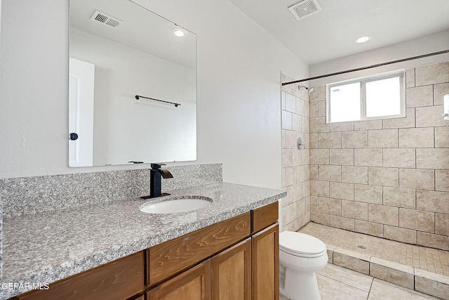 bathroom featuring vanity, tile patterned flooring, toilet, and tiled shower