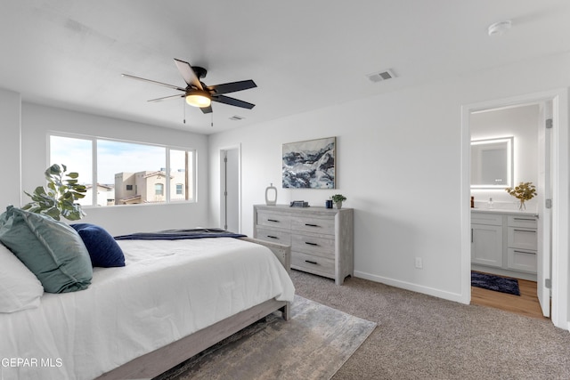 bedroom with light carpet, ceiling fan, and ensuite bath