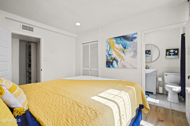 bedroom featuring wood-type flooring, a closet, and ensuite bathroom