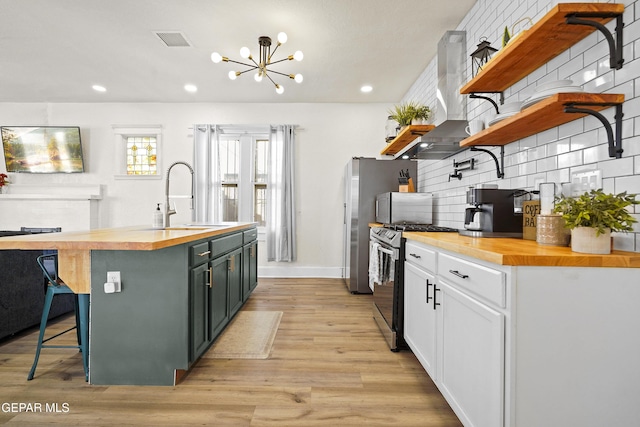 kitchen with stainless steel range with gas cooktop, sink, white cabinets, and wood counters