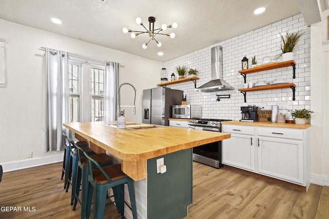 kitchen with white cabinetry, wooden counters, wall chimney exhaust hood, and appliances with stainless steel finishes