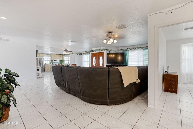 tiled living room featuring ceiling fan and a textured ceiling