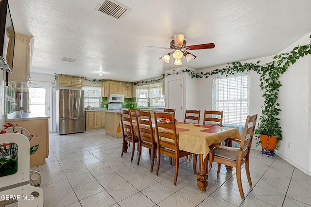 tiled dining space featuring a textured ceiling, plenty of natural light, and ceiling fan