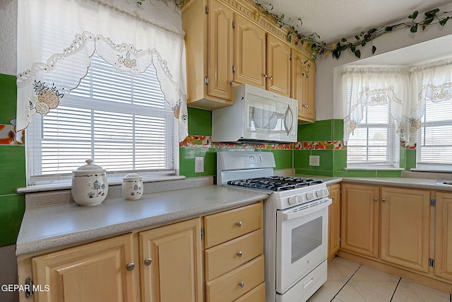 kitchen featuring light tile patterned floors, white appliances, plenty of natural light, and a textured ceiling