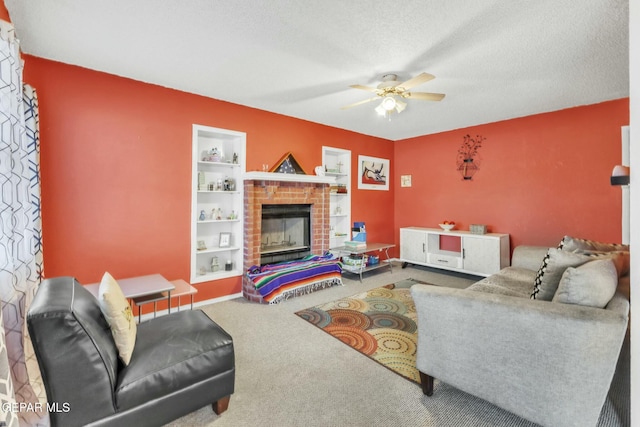 living room with built in features, carpet floors, a tiled fireplace, ceiling fan, and a textured ceiling