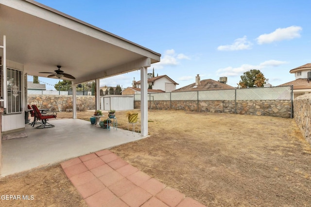 view of yard featuring a shed, ceiling fan, and a patio area