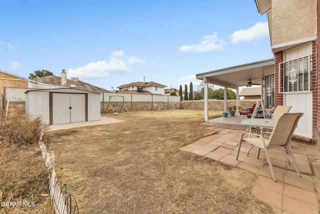 view of yard featuring ceiling fan, a shed, and a patio area