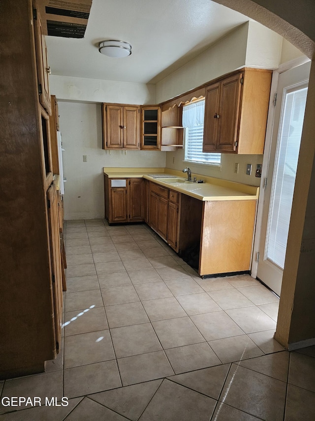 kitchen featuring open shelves, light countertops, a sink, and light tile patterned floors