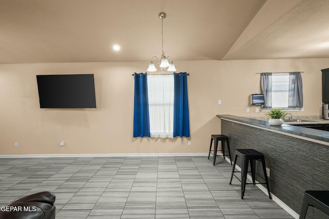 interior space with vaulted ceiling, sink, a breakfast bar area, and a notable chandelier