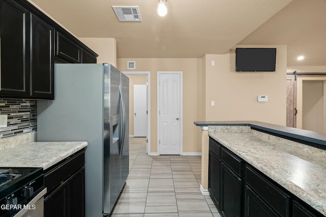 kitchen featuring stainless steel refrigerator with ice dispenser, a barn door, and backsplash