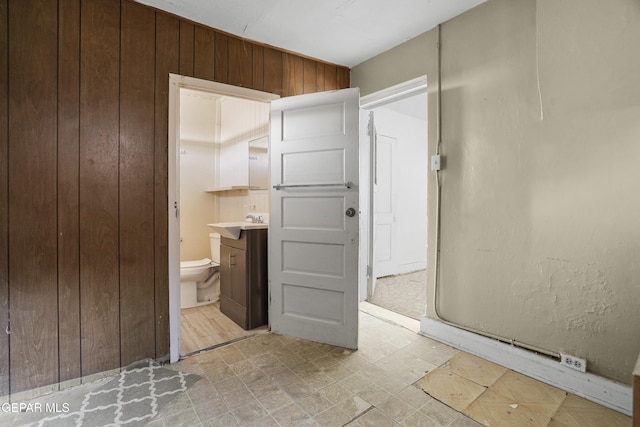 bathroom with vanity, toilet, and wood walls