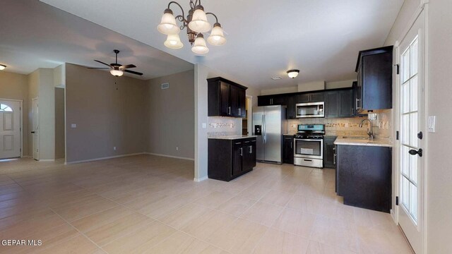 13749 Lorenz Ave, El Paso, TX 79928 - kitchen featuring sink, ceiling fan with notable chandelier, appliances with stainless steel finishes, light stone countertops, and decorative backsplash