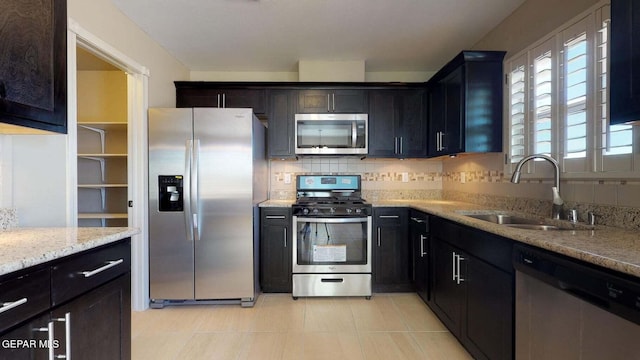 13749 Lorenz Ave, El Paso, TX 79928 - kitchen featuring appliances with stainless steel finishes, tasteful backsplash, sink, light tile patterned floors, and light stone counters