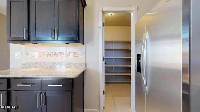 13749 Lorenz Ave, El Paso, TX 79928 - kitchen featuring stainless steel refrigerator with ice dispenser, dark brown cabinets, light tile patterned floors, light stone countertops, and decorative backsplash