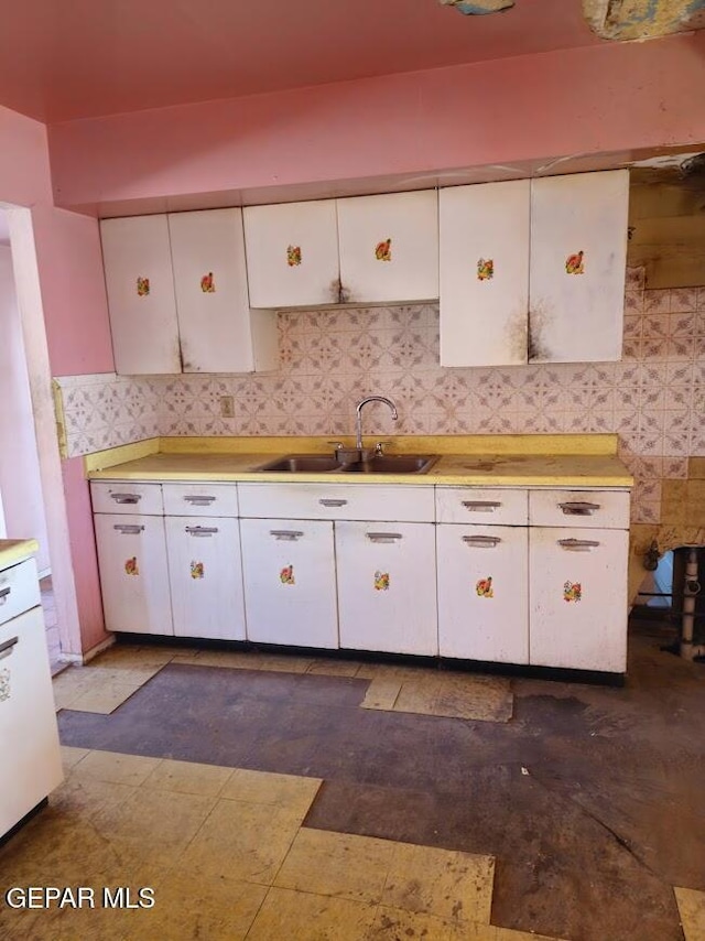 kitchen featuring sink, backsplash, and white cabinets