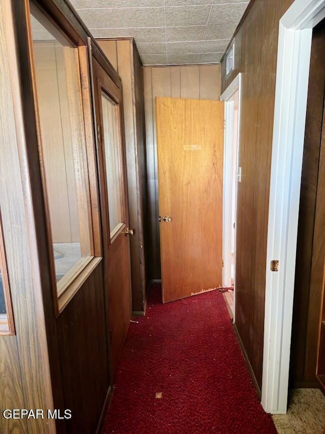 hallway with wooden walls and dark carpet