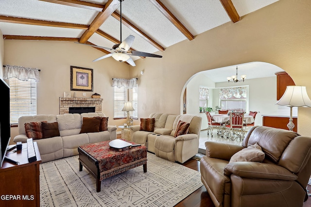 living room featuring lofted ceiling with beams, light hardwood / wood-style flooring, a textured ceiling, a fireplace, and ceiling fan with notable chandelier