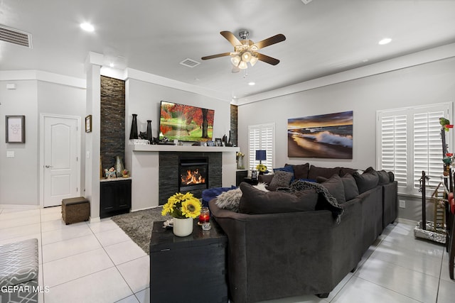 living room featuring light tile patterned flooring, ceiling fan, and a stone fireplace