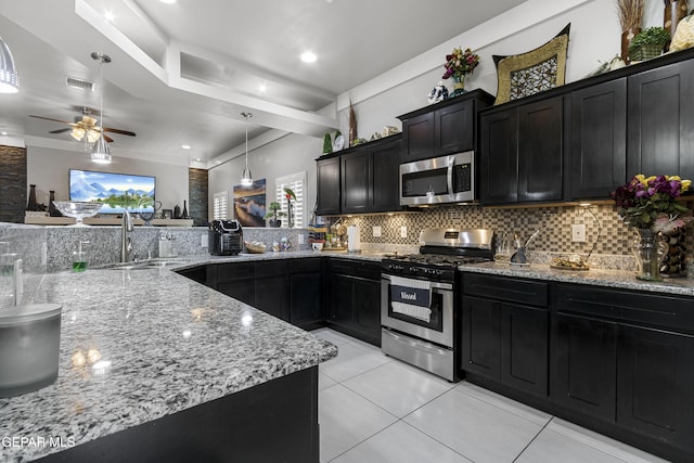 kitchen with appliances with stainless steel finishes, sink, decorative backsplash, hanging light fixtures, and kitchen peninsula