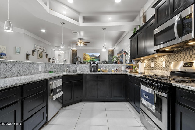 kitchen with pendant lighting, sink, backsplash, stainless steel appliances, and light stone countertops