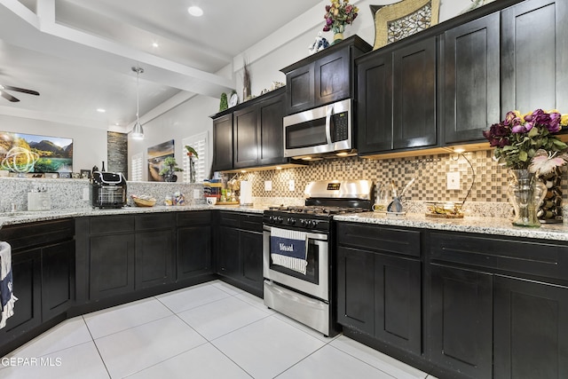 kitchen featuring stainless steel appliances, light stone countertops, backsplash, and decorative light fixtures