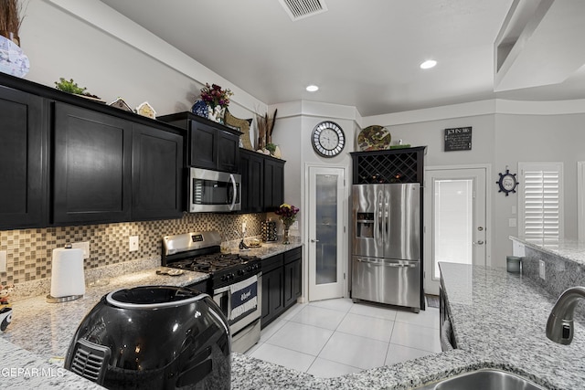 kitchen featuring light tile patterned flooring, sink, light stone counters, tasteful backsplash, and stainless steel appliances