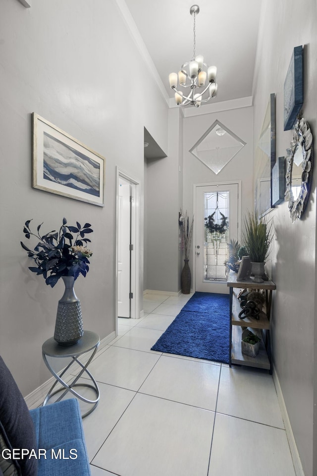 tiled foyer entrance featuring ornamental molding and a chandelier