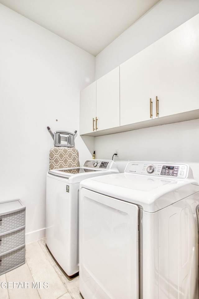 clothes washing area with cabinets, separate washer and dryer, and light tile patterned floors