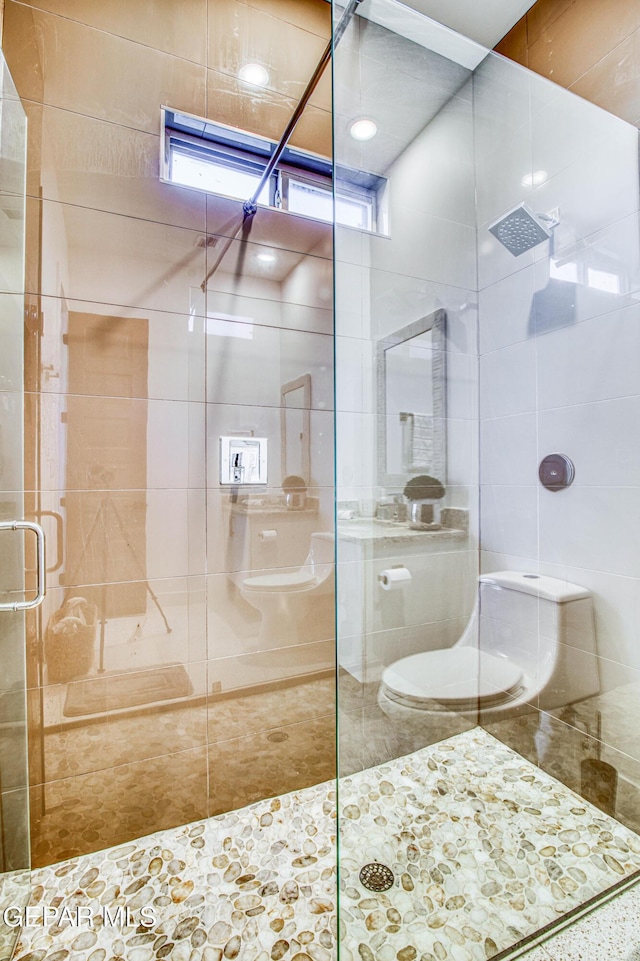 bathroom featuring toilet and a shower with shower door