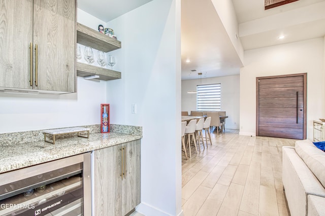 kitchen featuring beverage cooler, light stone counters, and light hardwood / wood-style floors