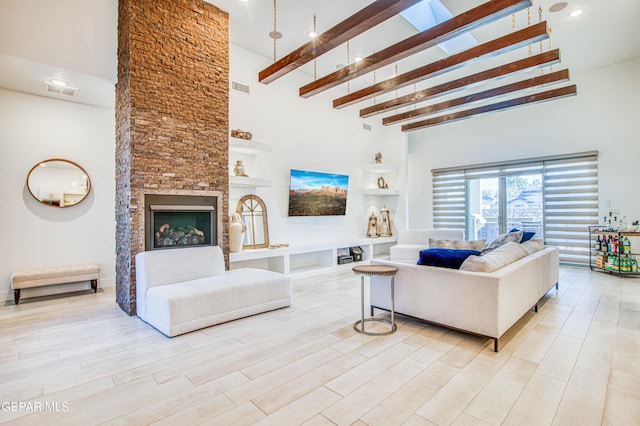 living room featuring beam ceiling, a high ceiling, a stone fireplace, and light wood-type flooring